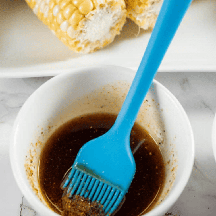 Whisking olive oil, lemon juice, and spices in a small bowl to season air fryer corn ribs