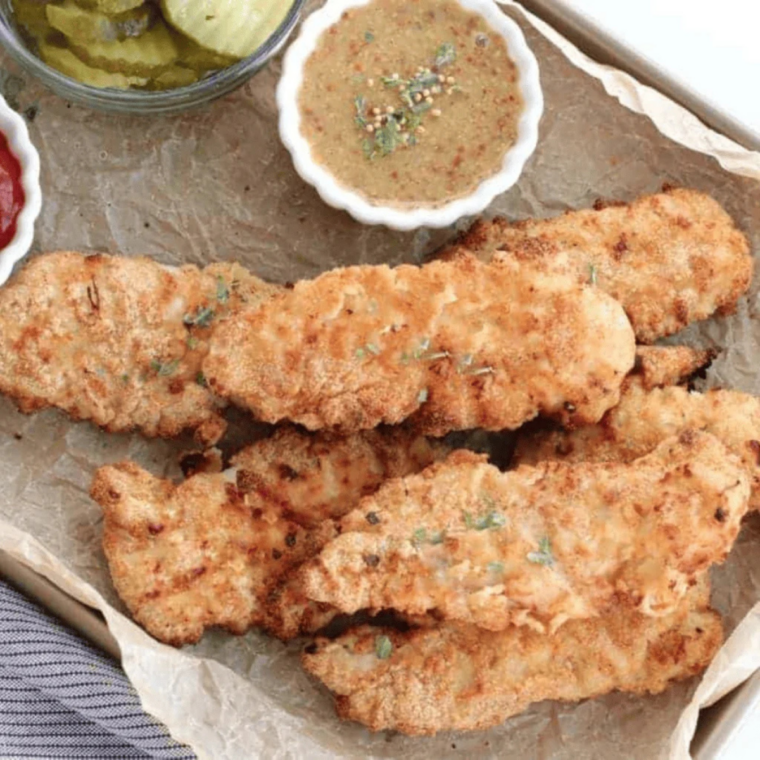 Air fryer cornbread crusted chicken tenders on a plate with pickles