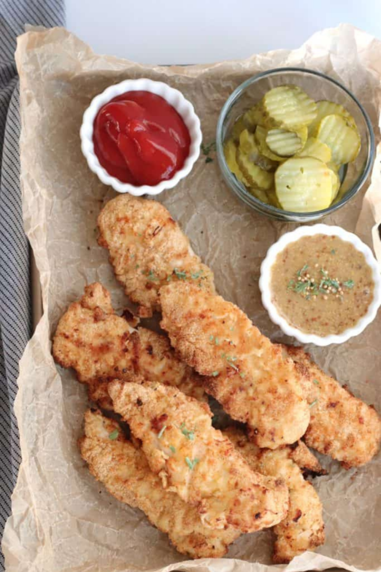 Plate of Jiffy cornbread crusted chicken tenders served with pickle spears