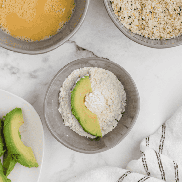 bowls with flour, eggs, and seasoned breadcrumbs arranged for coating avocado fries