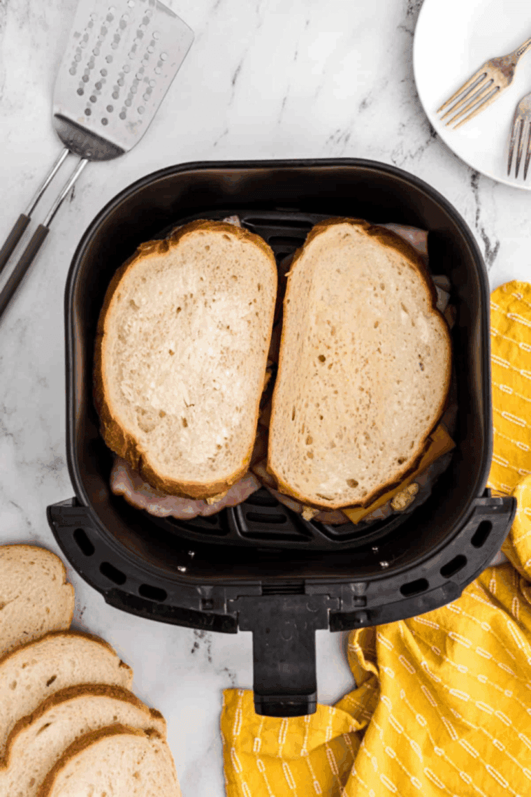 Air Fryer Moons Over My Hammy sandwich cut in half, showing the melted cheese, ham, and scrambled eggs between toasted bread.
