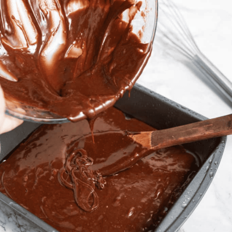 Air fryer vegan brownie batter spread in a parchment-lined pan inside the basket