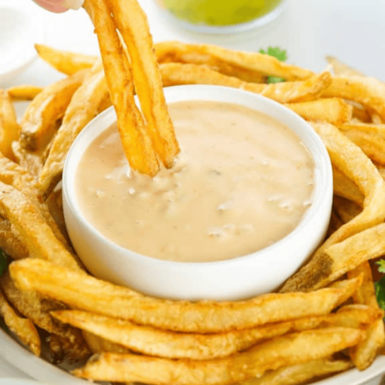 Golden skin-on copycat Wendy's fries piled on parchment with sea salt and ketchup