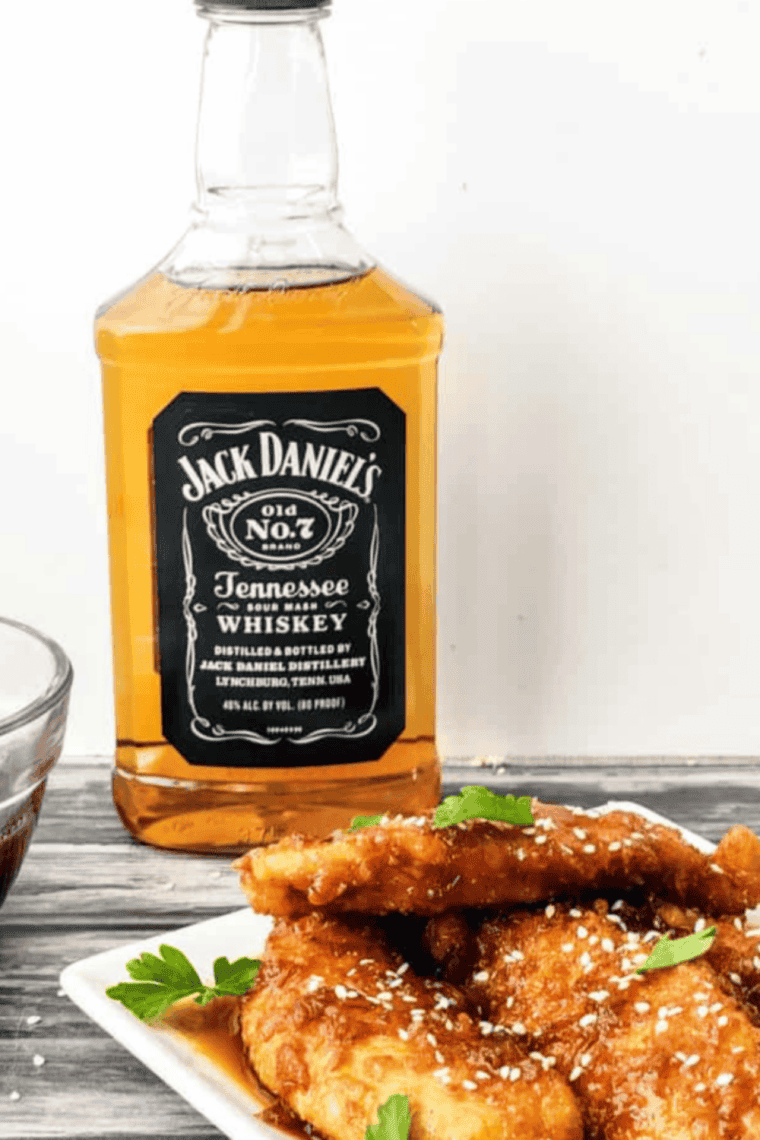 Plated copycat Jack Daniel's chicken strips with whiskey glaze, sesame seeds, and green onion.