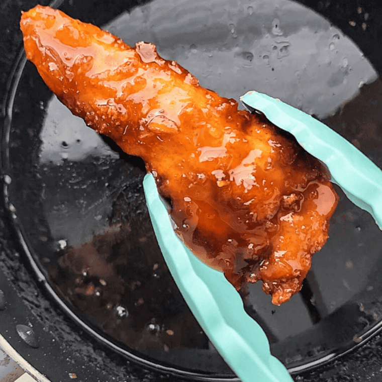 Tossing crispy chicken strips in warm Jack Daniel's whiskey glaze to coat both sides