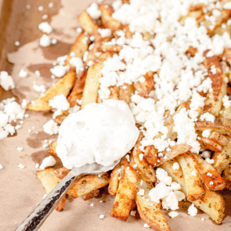 Golden air fryer Greek fries topped with feta, tzatziki, onions, and fresh parsley.