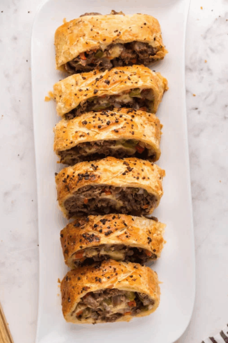 Golden-brown Italian Beef Stromboli sliced open, showing tender beef, saut&eacute;ed peppers and onions, and melted provolone cheese inside.