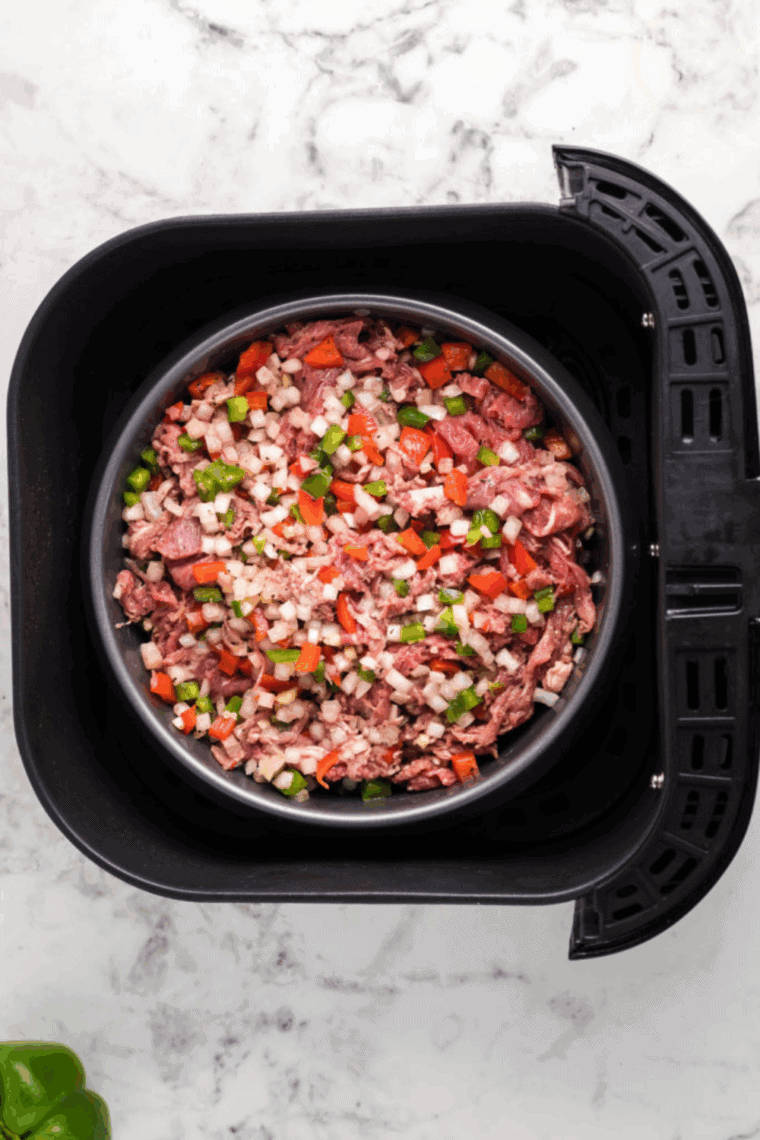 Italian beef and vegetables cooking in an air fryer, resting before next step.
