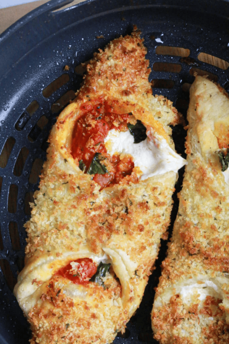 Golden Air Fryer Pizza Cannoli filled with melted mozzarella, tomato sauce, and fresh basil on a plate.