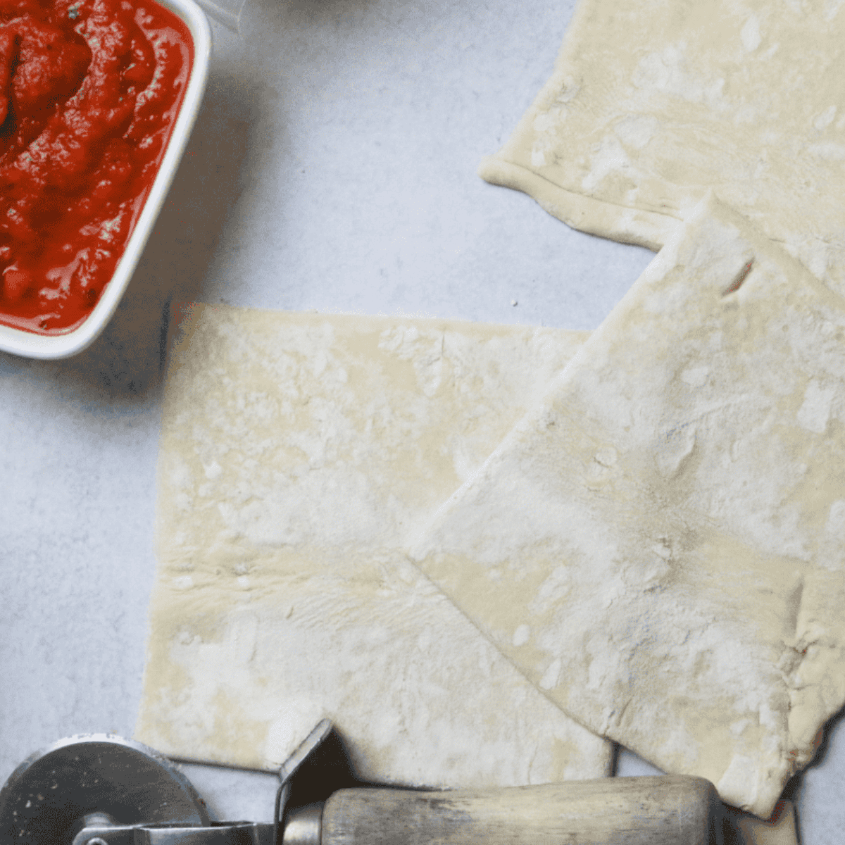 Puff pastry sheet cut into eight equal squares on a flat surface.