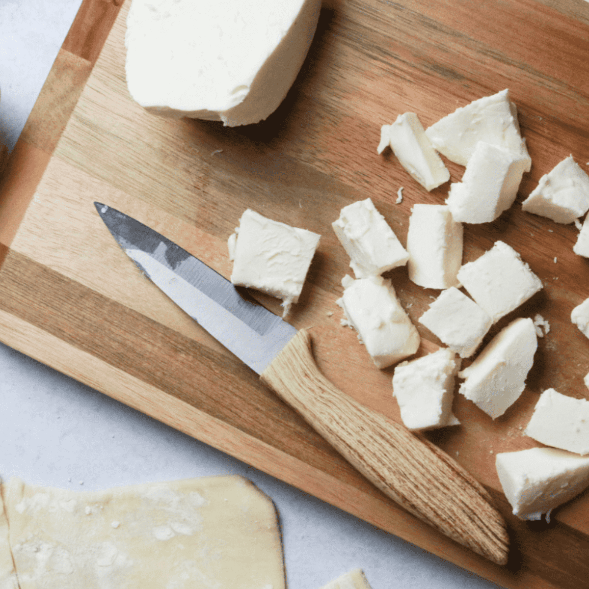 Mozzarella cheese cut into small cubes on a cutting board.