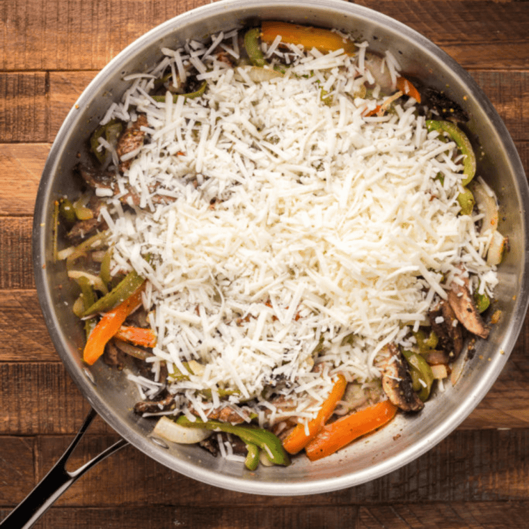 Vegan Philly filling in a skillet with melted Daiya cheese mixed with peppers and onions.