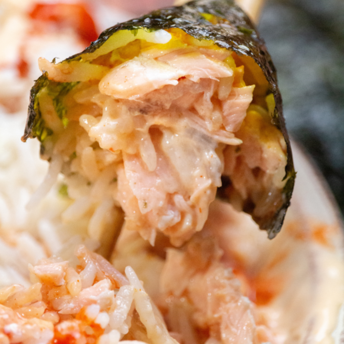 Close-up of homemade salmon sushi rolls with avocado and sticky rice on a bamboo mat
