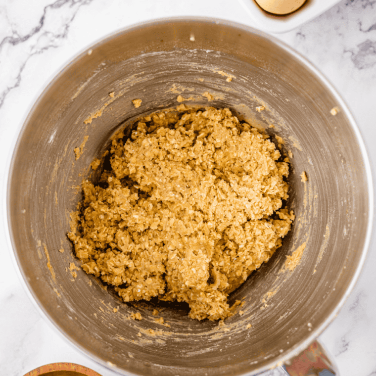 Air fryer basket lined with parchment paper holding flattened cookie dough balls ready to cook