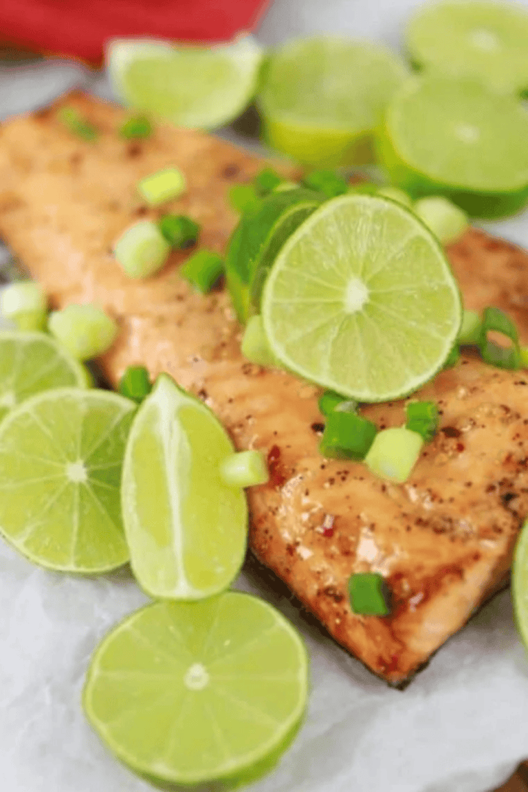 Air fryer firecracker salmon glazed with sweet chili sauce, topped with lime slices and diced scallions
