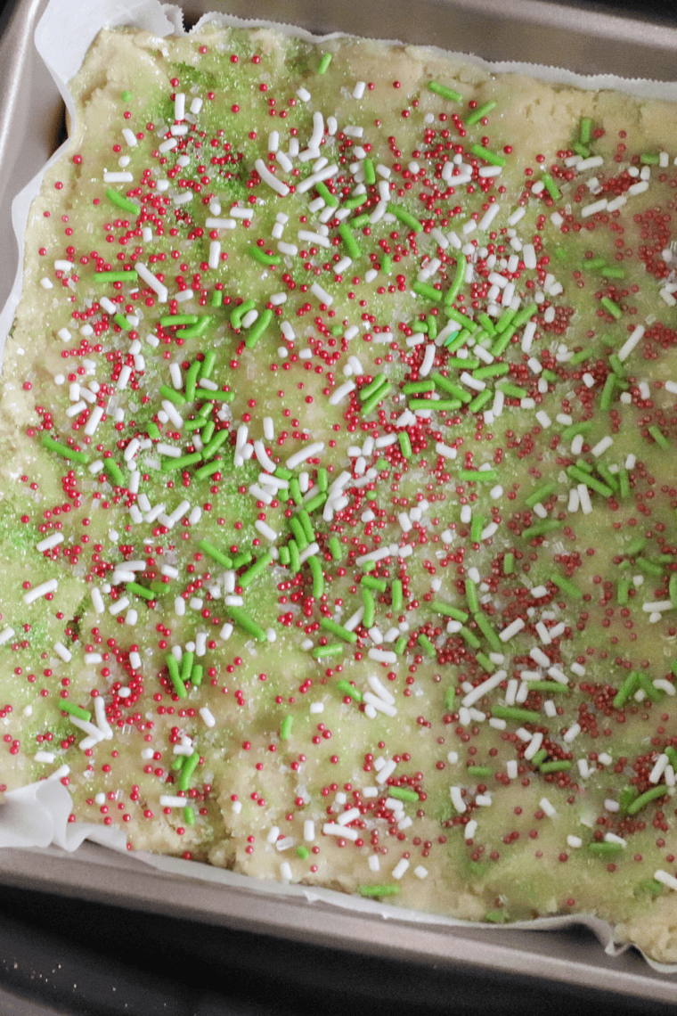 Sugar cookie dough topped with sprinkles in an air fryer pan, baking in the air fryer.