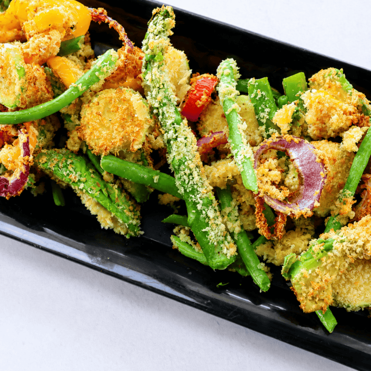 Plate of prepped raw vegetables for tempura including sliced zucchini, sweet potato, bell pepper, and green beans