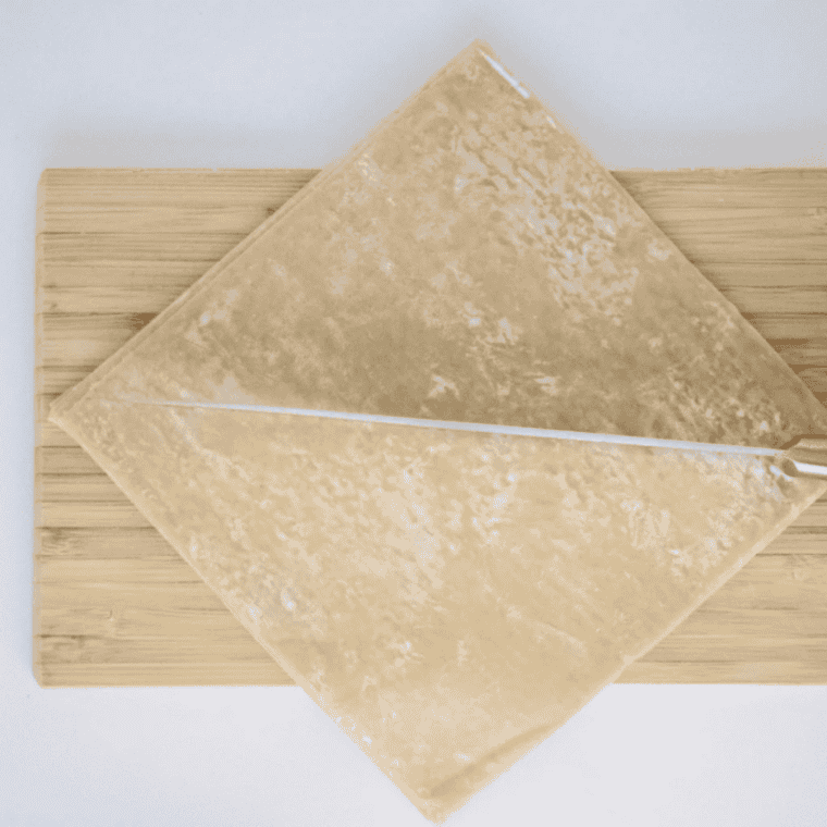 Wonton wrappers cut into triangles and brushed with oil on a cutting board