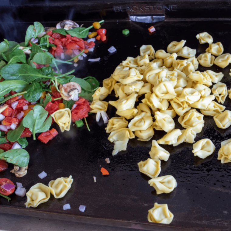 Blackstone tortellini cooked on griddle with sausage, cheese pasta, and vegetables