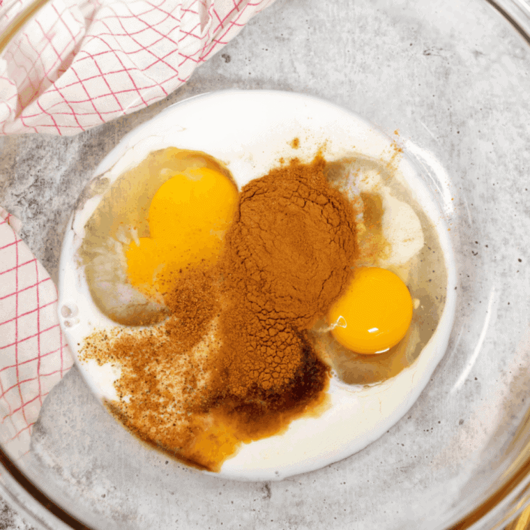 Whisking eggs, milk, vanilla, and cinnamon together in a shallow bowl
