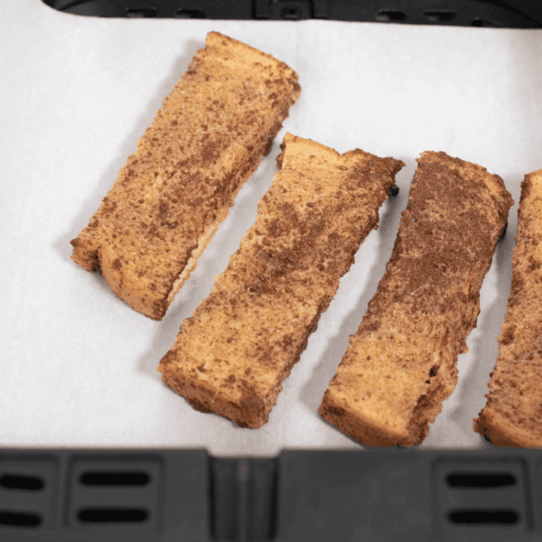 Dipping breadsticks into egg mixture and greasing air fryer basket