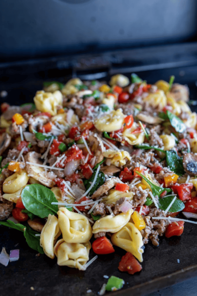 Close-up of sausage and cheese tortellini cooking on a flat top Blackstone grill