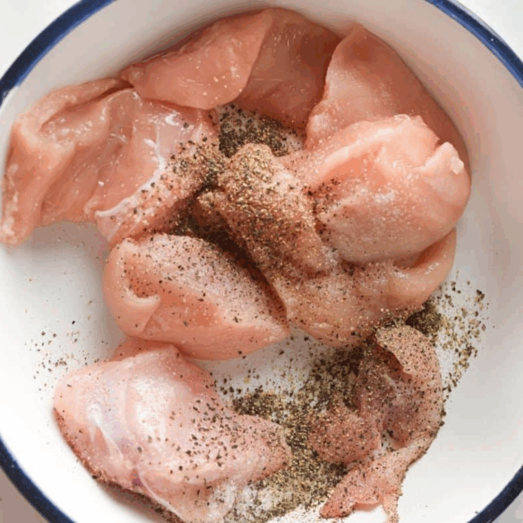 Chicken pieces coated with homemade basil, cashew, and Parmesan pesto in a mixing bowl