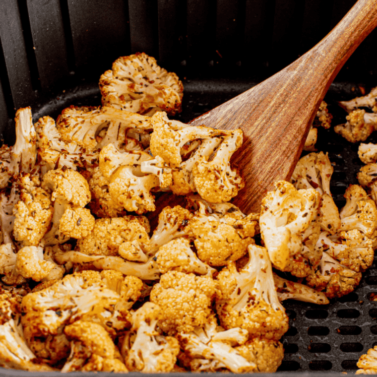Crispy air fryer frozen cauliflower served in a white bowl with herbs.