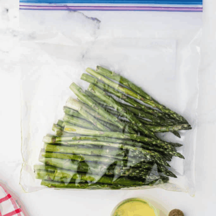 Washing and trimming woody stems from asparagus spears before tossing in seasoning bag.