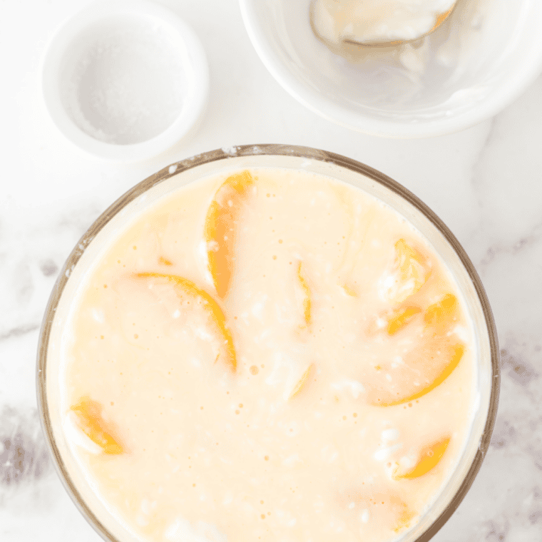 Frozen peach ice cream pint being placed into Ninja Creami for processing.