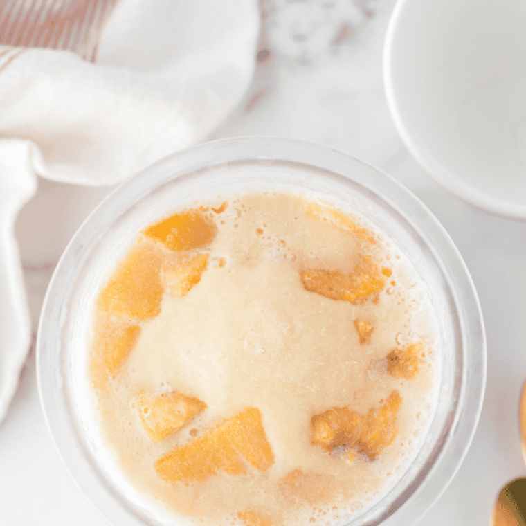 Adding milk to frozen peach ice cream in a Ninja Creami for a creamier texture before re-spinning.