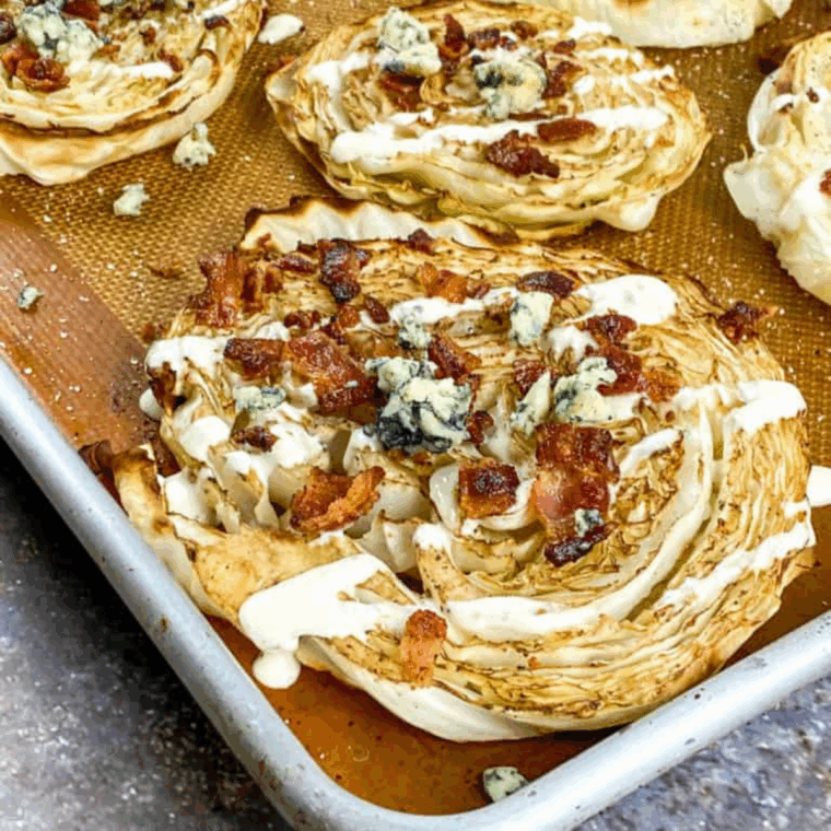 Crispy air fryer loaded cabbage steaks topped with melted cheese, bacon, and green onions on a plate.