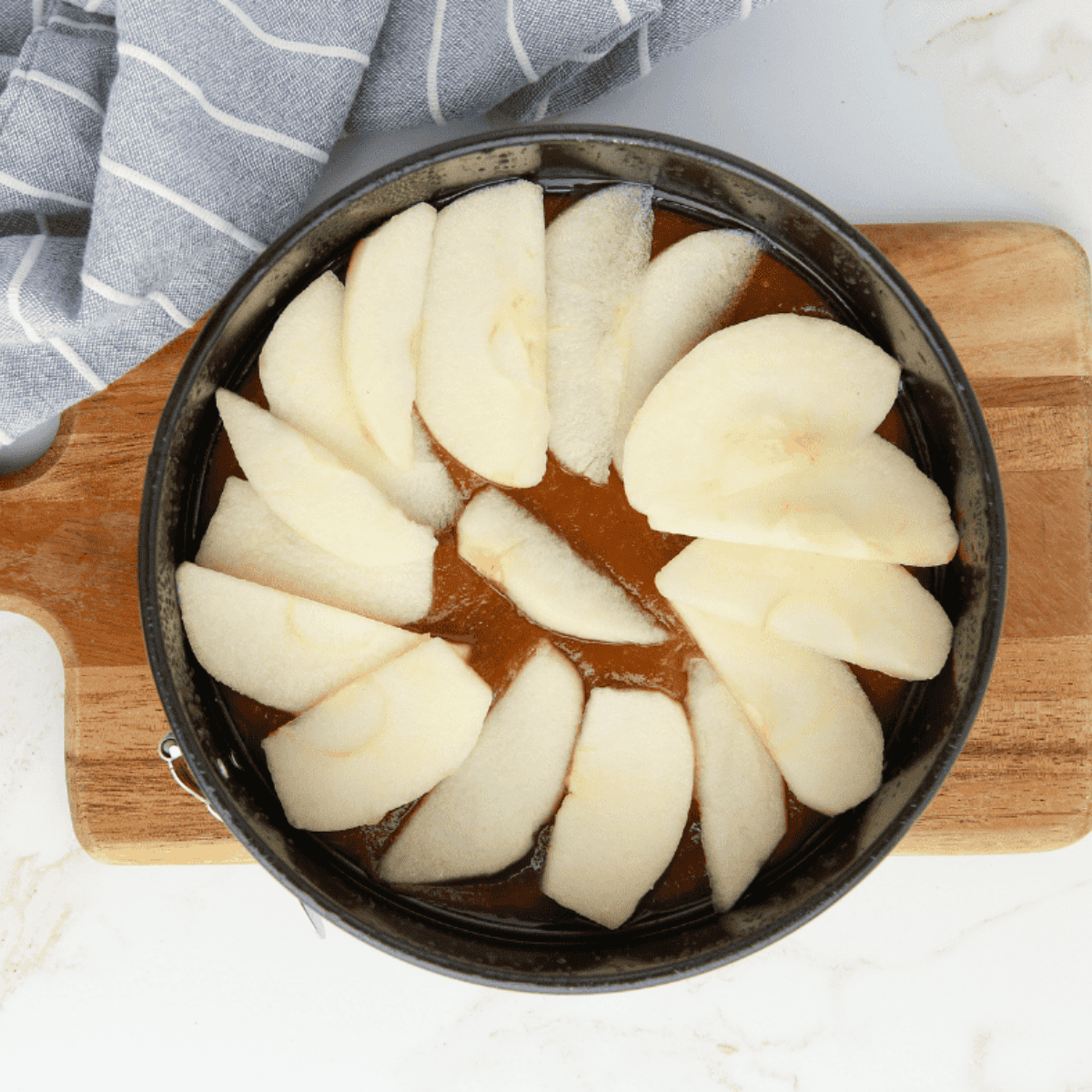 Pouring caramel sauce into pan and arranging apple wedges evenly on top