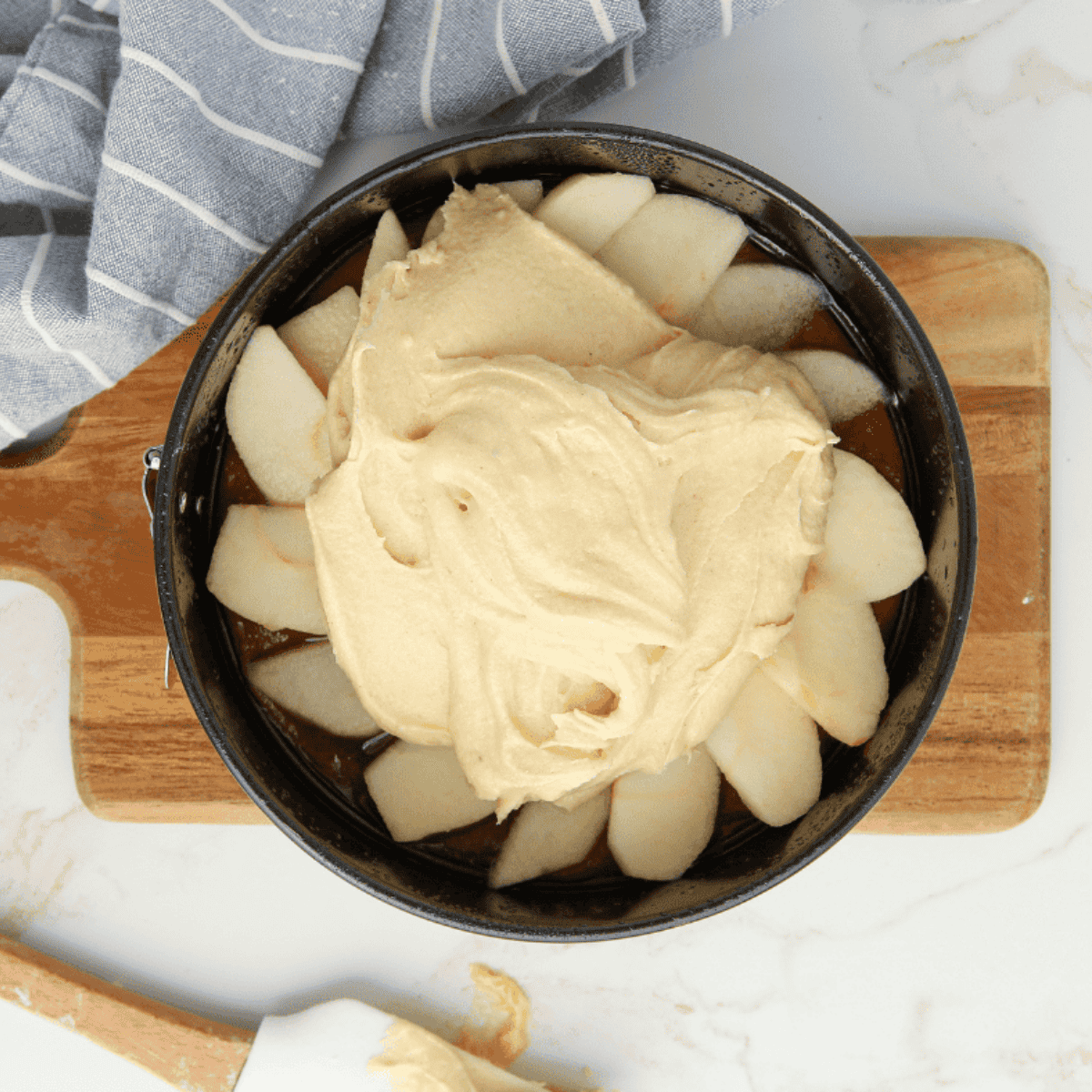Spreading cake batter evenly over caramel apple mixture in the pan