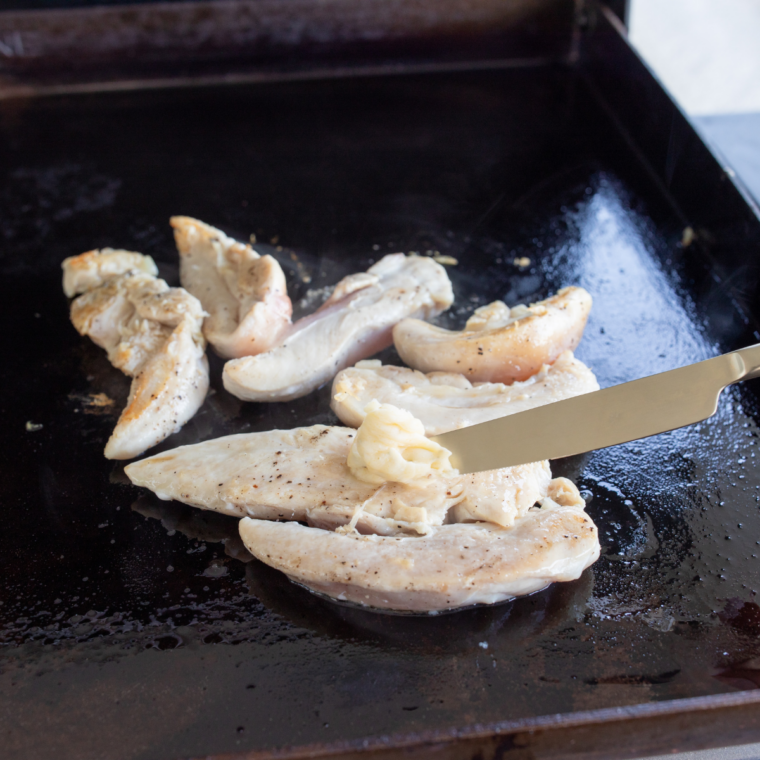 sliced juicy chicken breast on Blackstone griddle with spatula
