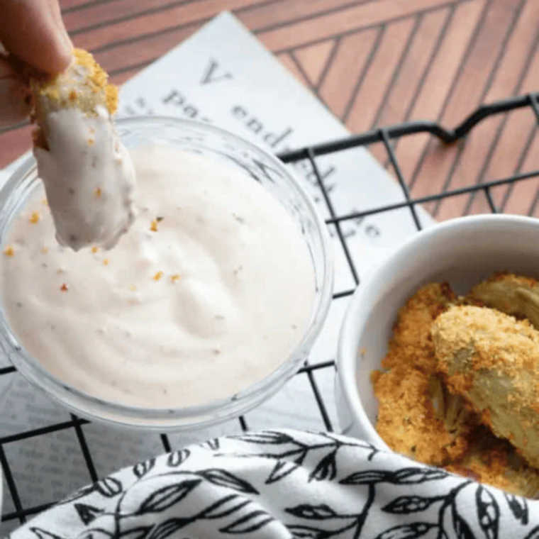 Crispy air fryer artichoke hearts being dipped into garlic aioli