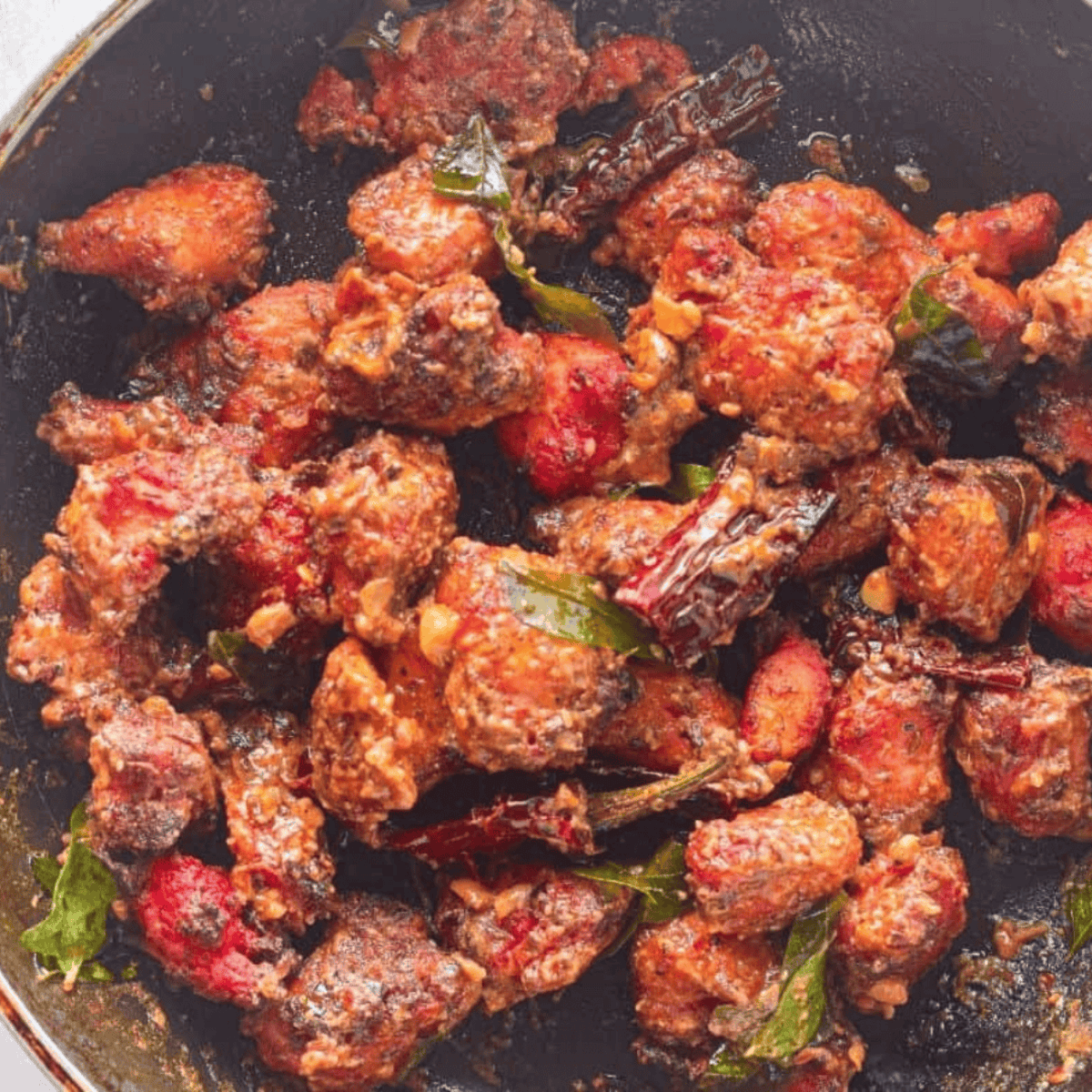 Plated Chicken 65 served with lemon wedges and garnished with fresh herbs.