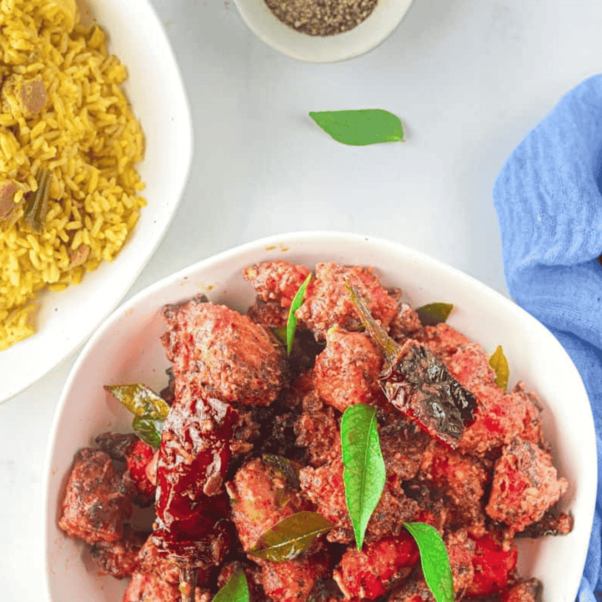 Plated Chicken 65 served with lemon wedges and garnished with fresh herbs.