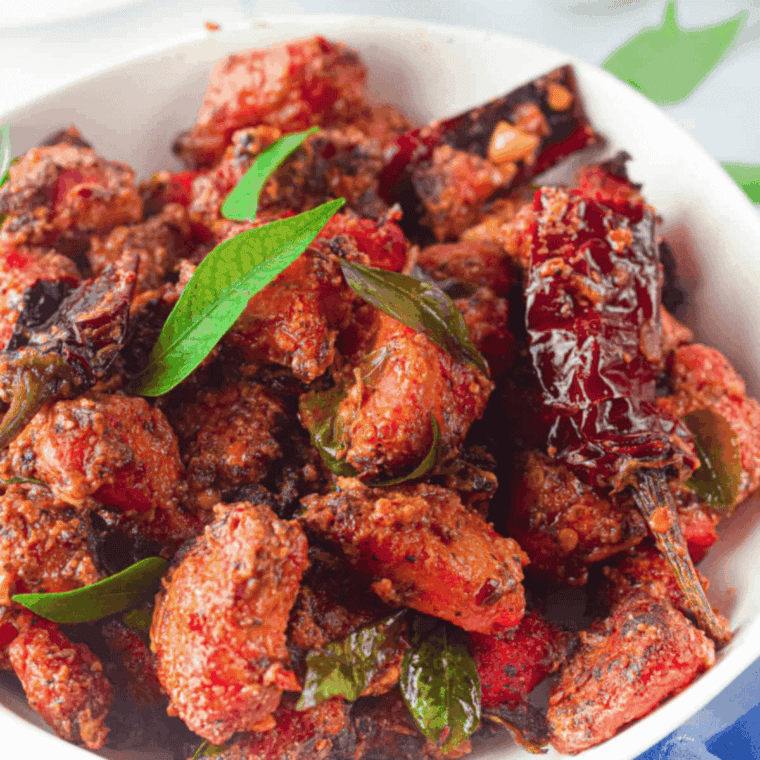 Crispy Air Fryer Chicken 65 garnished with curry leaves and red chilies.