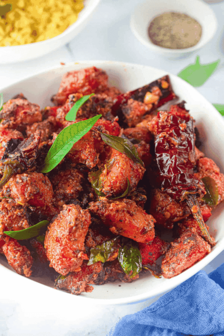 Plated Chicken 65 served with lemon wedges and garnished with fresh herbs.