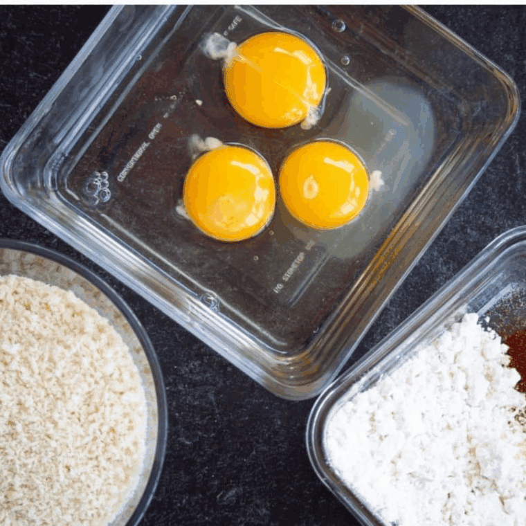  Three bowls set up for breading olives: one with whisked eggs, one with seasoned flour and spices, and one with Panko breadcrumbs.