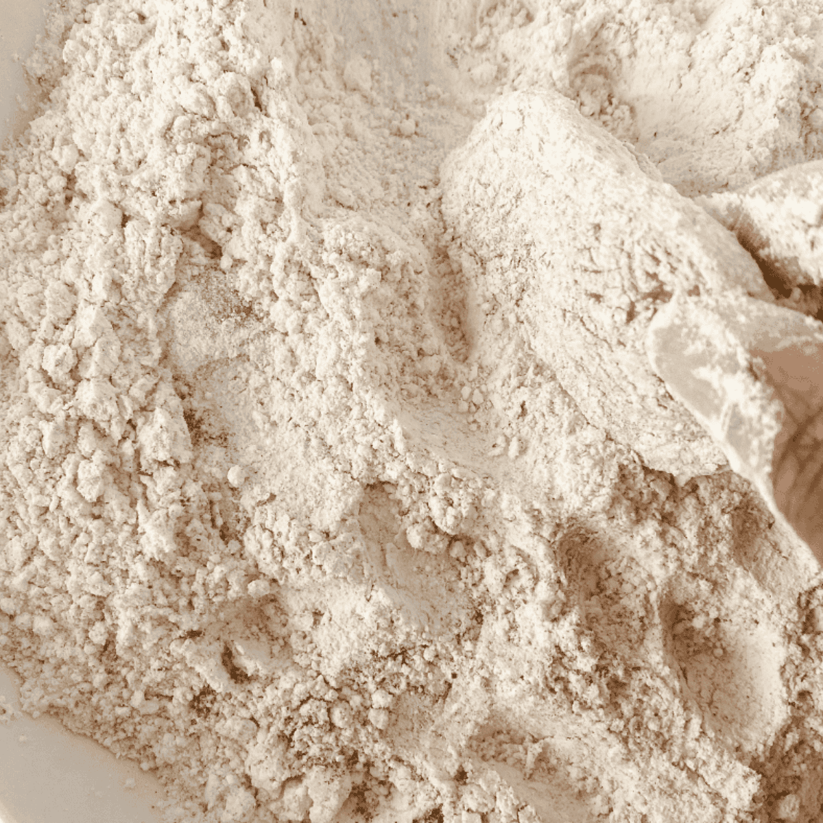 Chicken tenders being dipped in seasoned buttermilk, then dredged in flour on a wire rack breading station