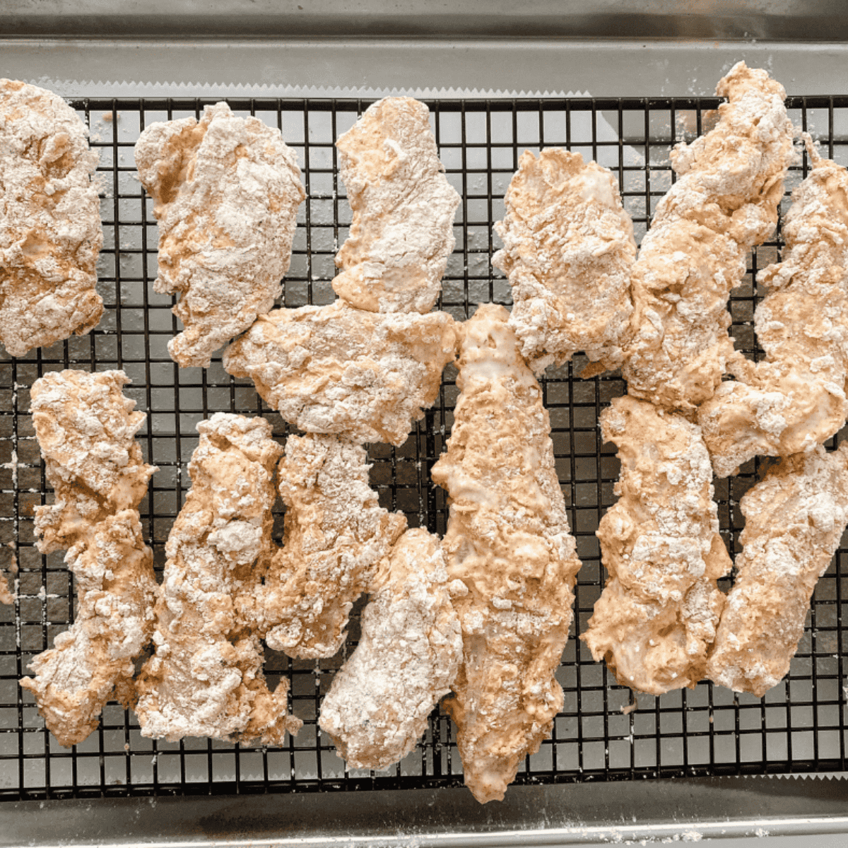 Breaded chicken tenders resting on wire rack, then air fried until golden and crispy