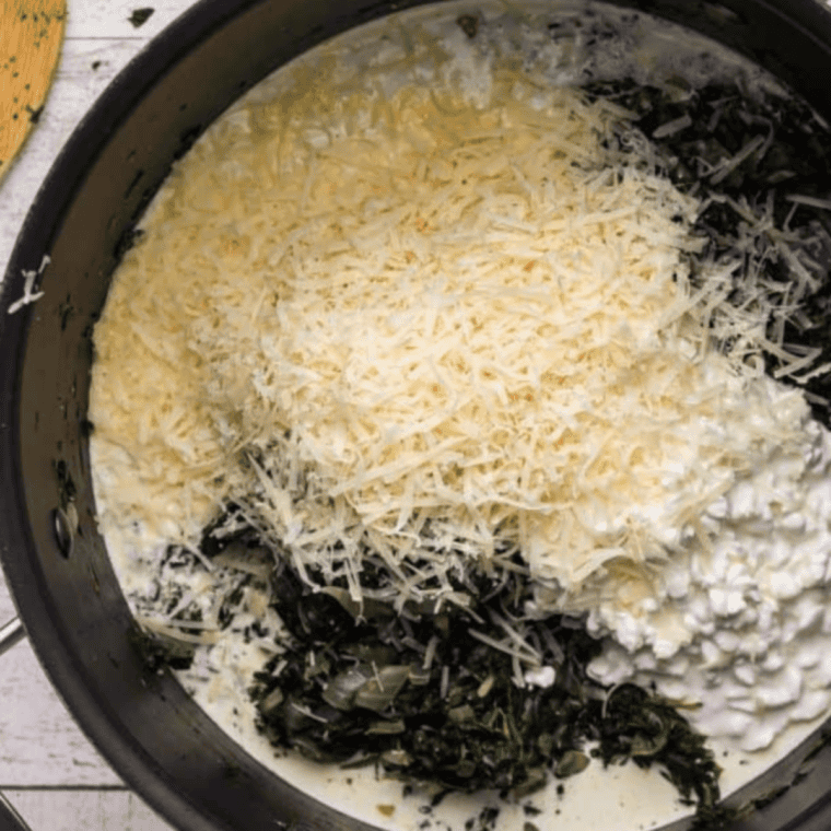 Spinach, onions, and spices cooking in a pot on the stove, being stirred before cooling and mixing with quiche filling ingredients.