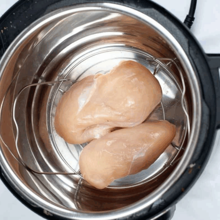 Raw chicken breast in Instant Pot with water before cooking on high pressure