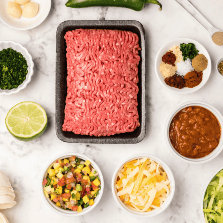 Ingredients for Cuban picadillo stuffed peppers, including bell peppers, ground beef, green olives, raisins, and capers