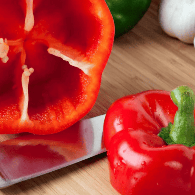 Hollowed bell peppers with tops sliced off and seeds removed on a cutting board