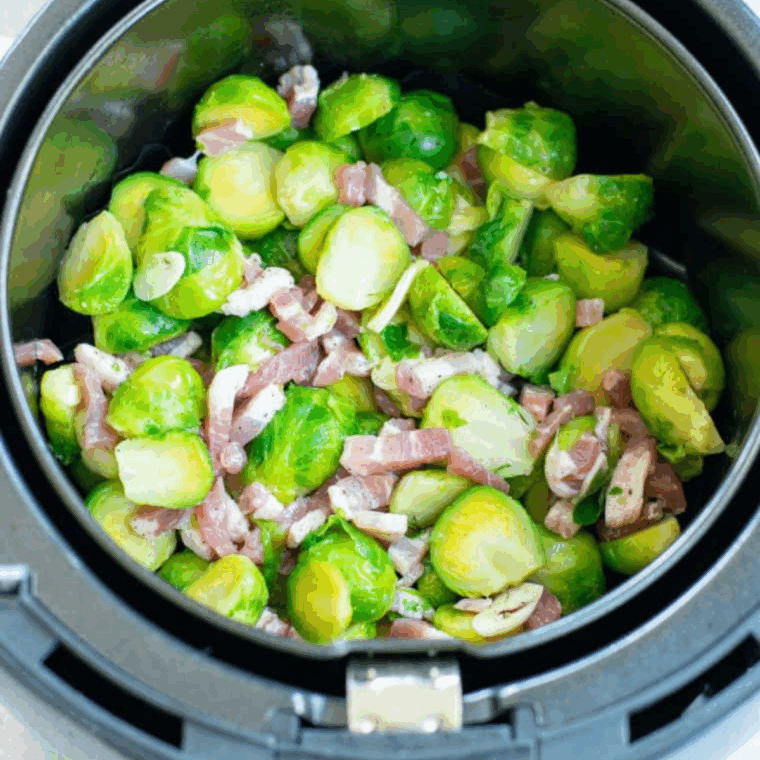 Preheating air fryer and arranging Brussels sprouts with bacon evenly for cooking.