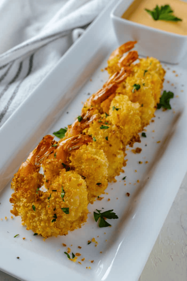 Crispy golden Bang Bang Shrimp coated in creamy sweet and spicy sauce served on a plate with lettuce garnish for a restaurant-style appetizer at home.