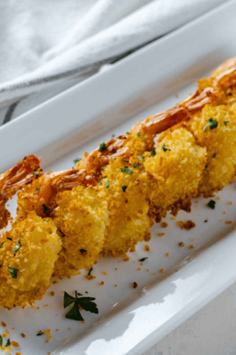Crispy golden Bang Bang Shrimp tossed in creamy sweet and spicy sauce served on a plate with lettuce garnish for a restaurant-style appetizer or meal.